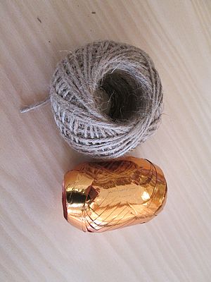 Zur Aufhängung der fertigen Zapfensterne wird Juteband benötigt, die Dekoschleife entsteht aus goldenem Geschenkband